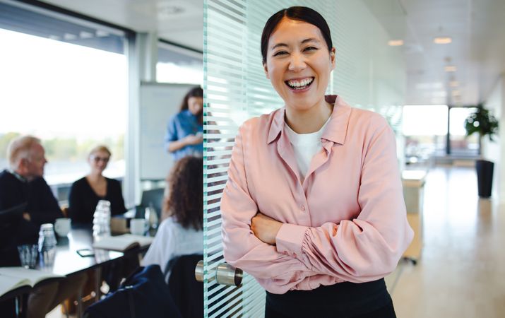 Cheerful female professional with colleagues sitting in boardroom at the back