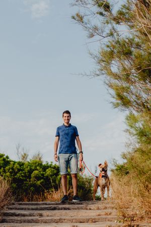 Happy adult man walking with dog along rural pathway