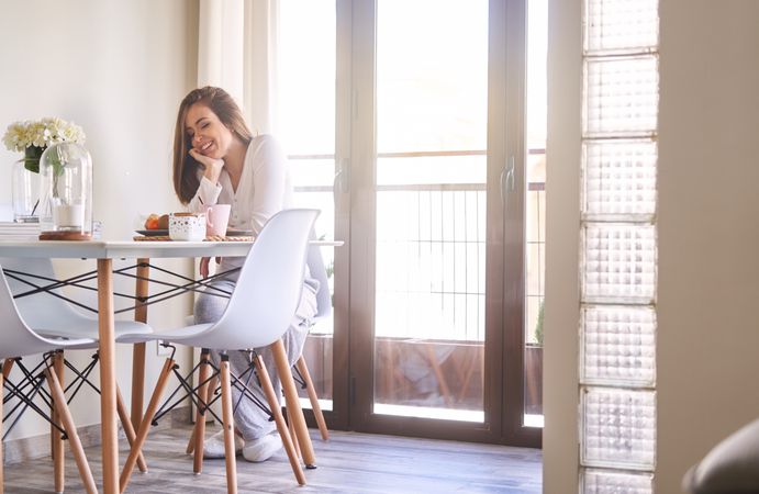 Smiling woman eating at table at home