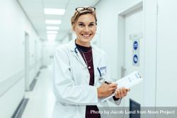Portrait of happy young female doctor standing in hospital corridor 4jEoJ5