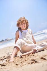 Smiling boy sitting on sandy beach near sea
