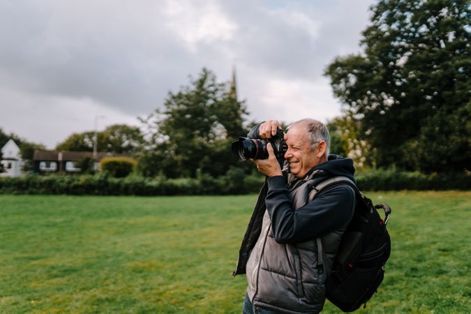 Older man taking a picture in a field