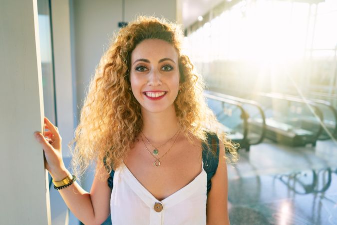 Pleasant woman in sunny hall of airport looking away