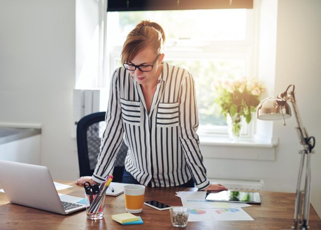 Female entrepreneur leaning on her desk in bright office