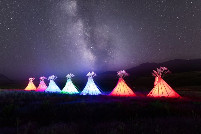 Montana, United States - August 17, 2022: Row of illuminated teepees under starry sky