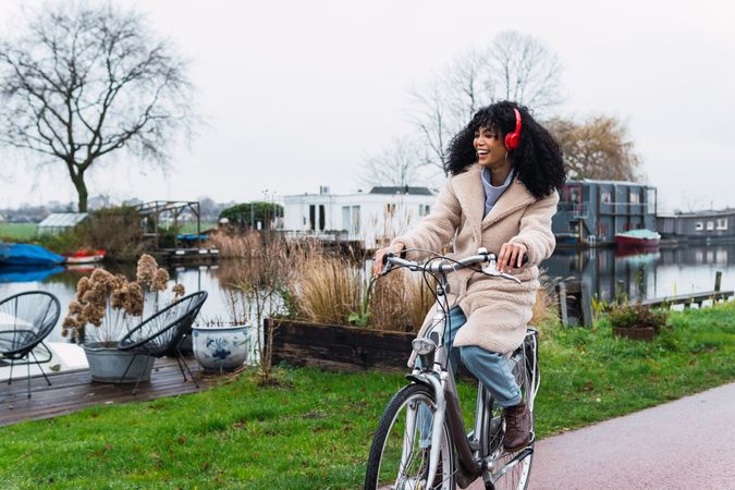 Excited Black woman in headphones riding bicycle