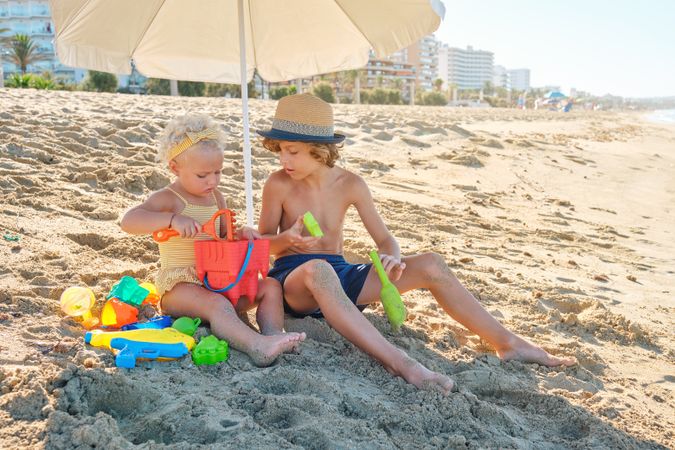 Little boy and girl playing with toys on beach