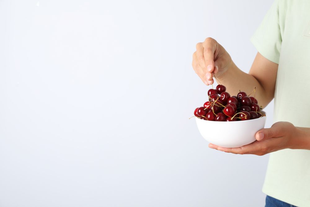 Ripe cherry fruits in a bowl on a light background