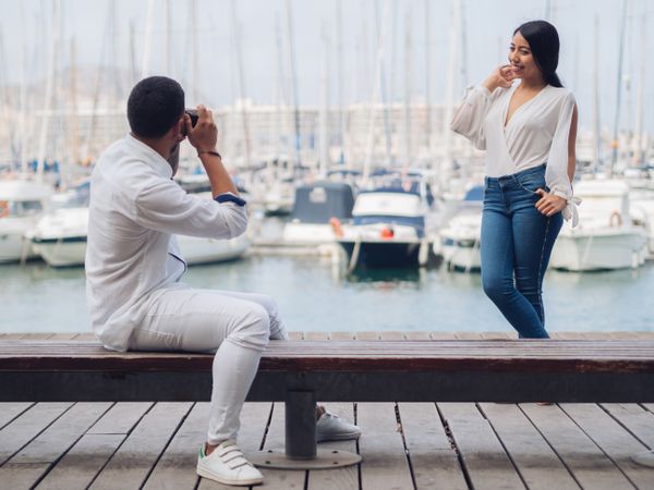 Woman taking photo and sitting with man on bench