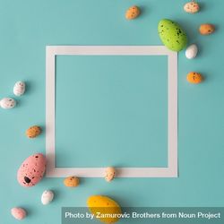 Easter composition made with colorful eggs on bright blue background with paper square outline 0VzRY0