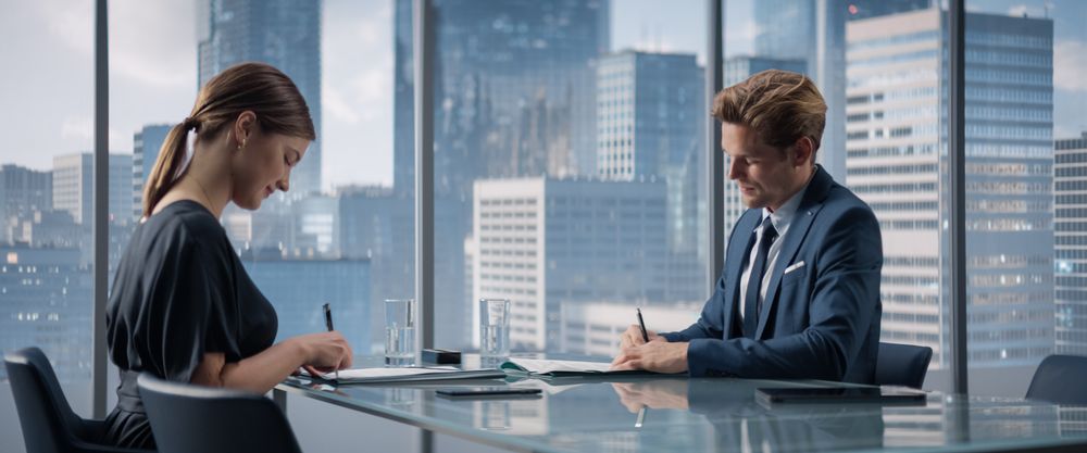 Female and Male Business Partners Sign Successful Deal and Shake Hands in Meeting Room in Skyscraper Office.