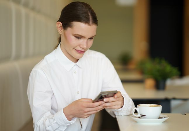 Businesswoman using phone in a chic cafeteria