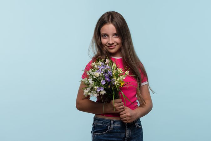Girl holds bouquet of flowers, smiling softly