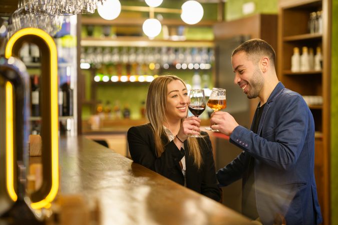 Happy man and woman toasting beer and wine at a bar or lounge