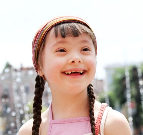 Portrait of a girl with Down syndrome with braids and a pink headband