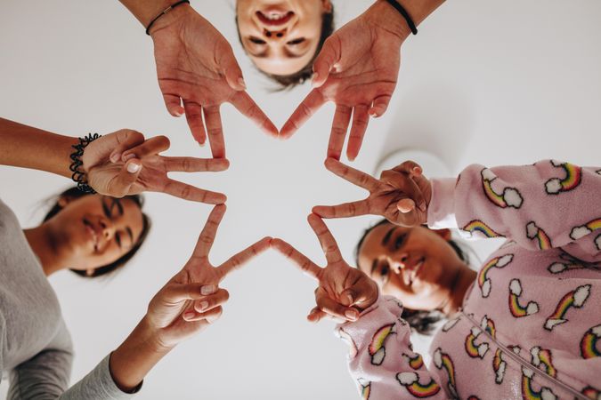 Low angle shot of friends making a star shape with their fingers