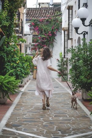 Woman walking downstairs with dog on narrow street