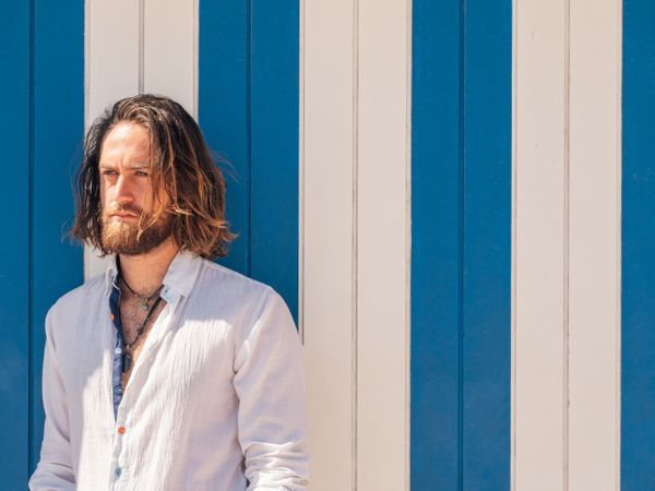 Cheerful guy standing near striped wall