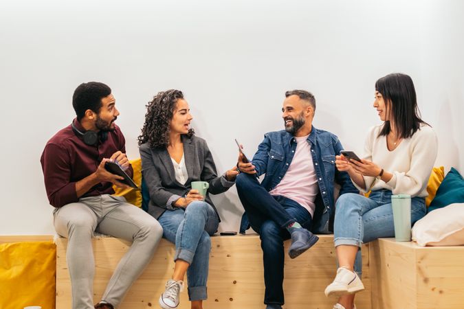 Coworkers in an informal meeting during a break. They discuss company data while having coffee in the break area of the modern coworking office