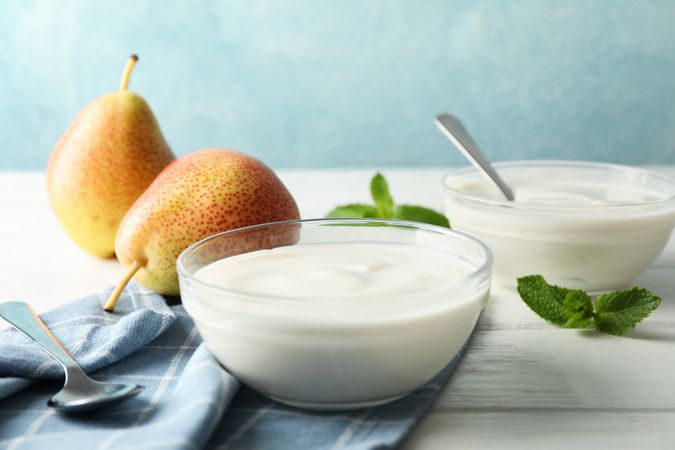 Composition with cream yogurts and fruits on light table, space for text