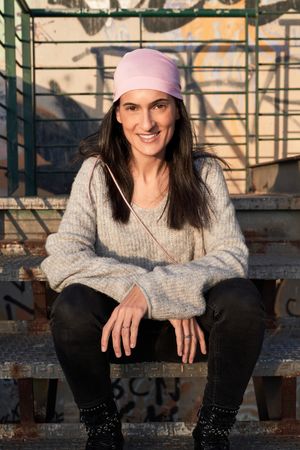 Smiling woman in pink scarf sitting on industrial stairs