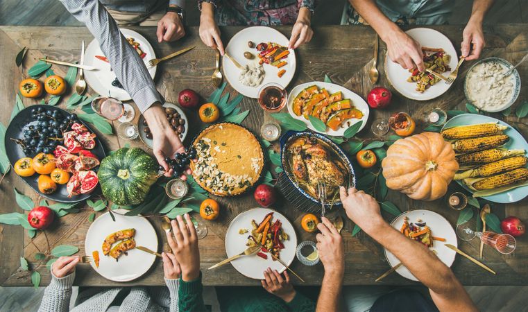 Top view flat lay of Thanksgiving food with people’s hands serving