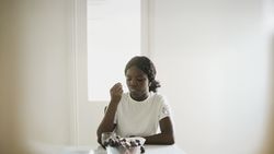 Black Woman Sitting at Dining Table Enjoying a Nutritious Snack.