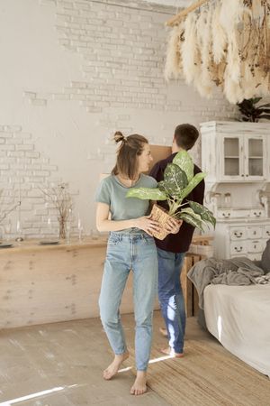 Active couple arranging flowers and stuff in new house