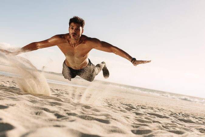 Young male doing jump push-up on the beach