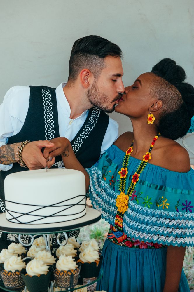 Bride and groom share a kiss while cutting the wedding cake