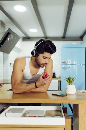 Young man in headphones holding apple