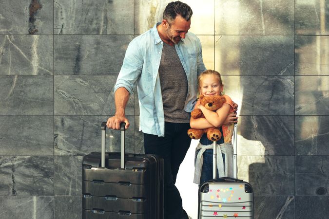 Father and daughter standing in airport with luggage