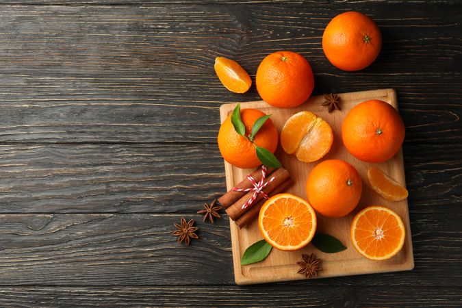 Board with mandarins and cinnamon on wooden background
