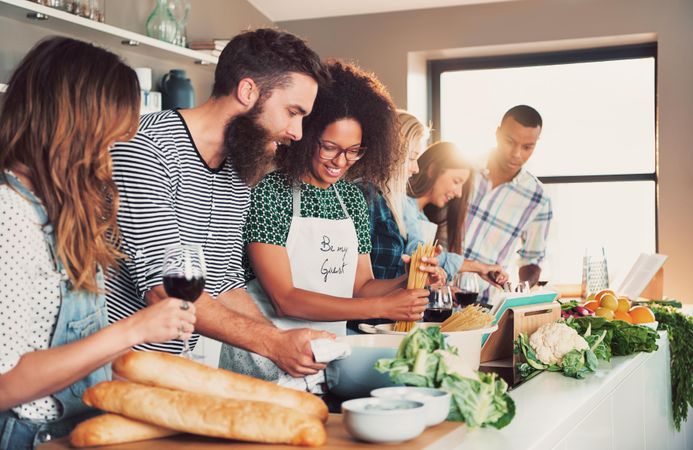 Six friends cooking pasta in a healthy kitchen with win