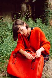 Woman straightening belt on suitcase in road
