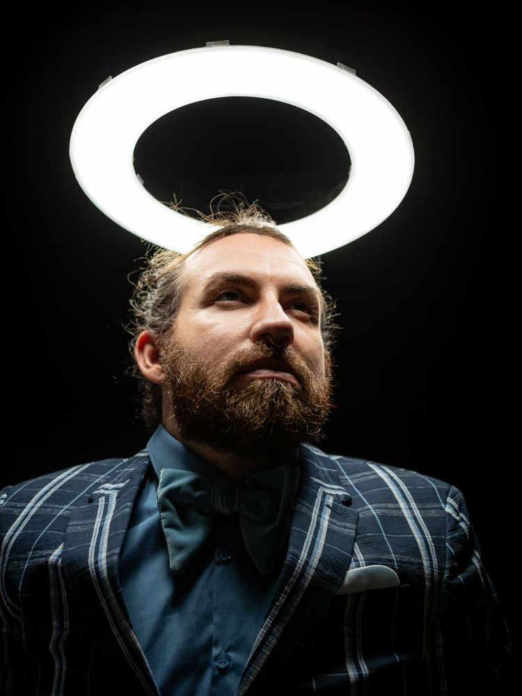 Smart bearded man under circle light on black background