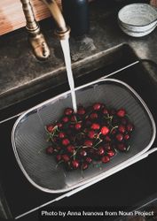 Cherries being washed in strainer over kitchen sink 0JE98b