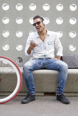 Male listening to something funny on phone while sitting with bike