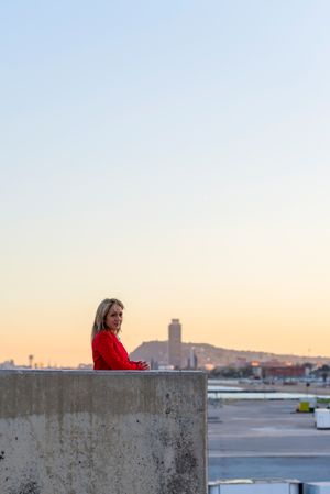 Woman in red coat standing on top of building with view of city
