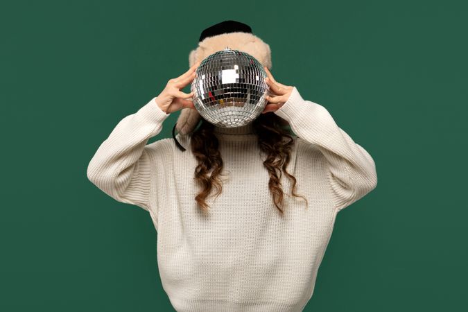 Girl playfully covering face with reflective disco ball