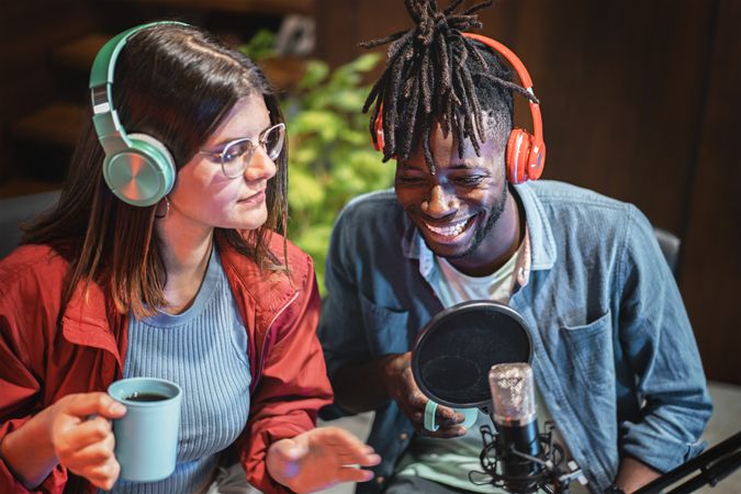 Multi-ethnic couple wearing headphones talking on the microphone making a vlog episode of their streaming video blog