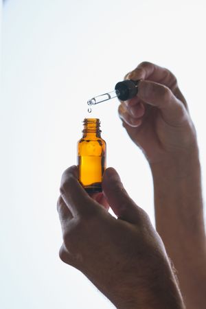 Crop person with bottle of serum