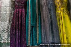 Colorful and patterned dresses hang in the market 5kMBAb