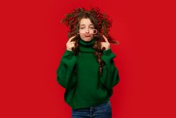 Young girl in green sweater balancing candy cane mustache