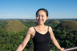 Happy woman standing on observation deck on hill