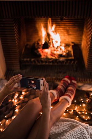 Crop female taking picture of fireplace