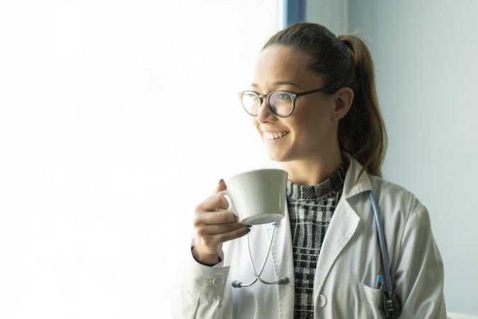 Smiling young doctor with cup