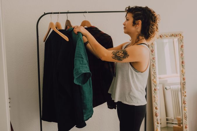 Happy woman hanging clothing on clothes rail at home