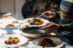 Man in bright sweater serves rustic roast vegetables