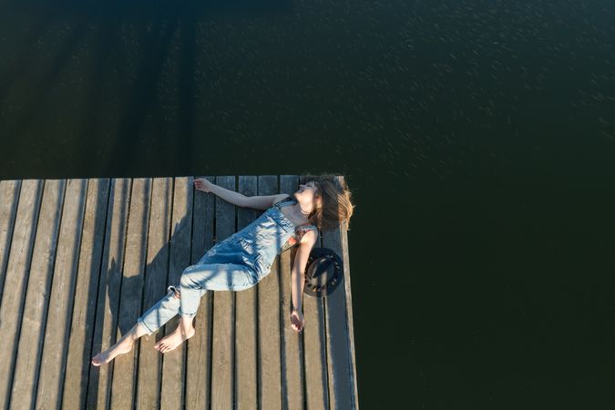 Young female lying down on pier on nature